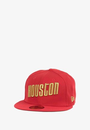 Red snapback cap with "HOUSTON" in gold, thick embroidery. Features flat brim, seven-panel design, and vent eyelets. New Era branding on side.