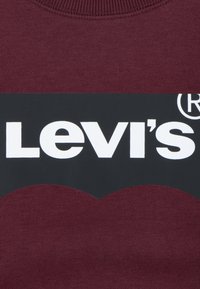 Felpa color bordeaux con un pannello logo nero che presenta la scritta bianca "Levi's". Collo a coste e texture morbida.