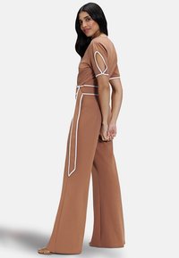 Brown jumpsuit with short sleeves, white accents, a belted waist, and wide-leg design. Smooth texture with a fitted bodice.