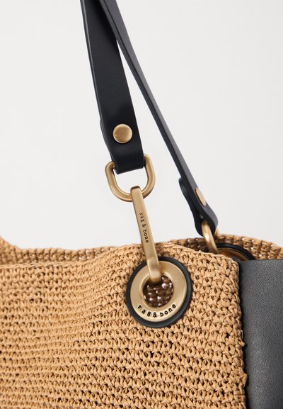Brown woven tote bag with a textured surface; features black leather straps and brass hardware with a logo detail on one side.