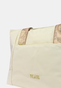 Borsa tote beige con tessuto testurizzato, finitura liscia e hardware dorato. Presenta bretelle con motivo e una tasca frontale con zip.