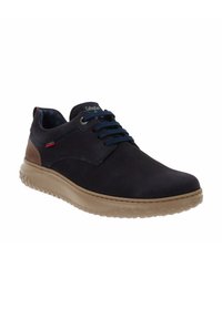 Zapato de cuero azul marino oscuro con suela de goma marrón, puntera redonda y cordones azules en contraste. Presenta un pequeño acento rojo y blanco en el lateral.