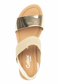 Beige sandaal met een glanzende metallic band en een zachte stoffen kruisb strap. Soepel voetbed met subtiele stiksels.