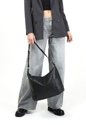 Borsa a spalla in pelle nera con una finitura morbida e testurizzata, caratterizzata da una forma curvata, tracolla regolabile e accessori in metallo argentato.