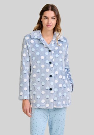 Chaqueta de forro polar azul claro con lunares blancos y azul claro, cierre de botones, cuello con solapa y bolsillos laterales. Pantalones a juego con lunares.