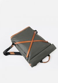 Grüner wasserdichter Rucksack mit braunen Lederakzenten, Rolltop-Verschluss und verstellbaren Trägern. Verfügt über eine äußere Reißverschlusstasche.