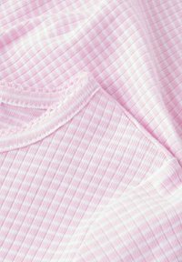 Růžová bavlněná látka s malým kostkovaným vzorem. Textura je jemná a okraje mají zdobený design podél výstřihu.