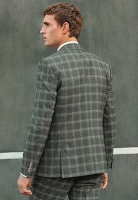 Completo a quadratini grigio con vestibilità su misura, caratterizzato da una silhouette strutturata, tessuto testurizzato e due bottoni sui polsini.