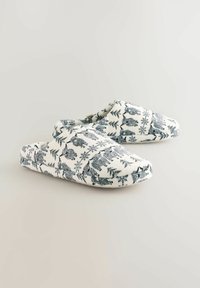 Katoenen instappers met een witte achtergrond en een blauw dieren- en loofpatroon. Rondneus en zachte textuur, ideaal voor binnenshuis gebruik.