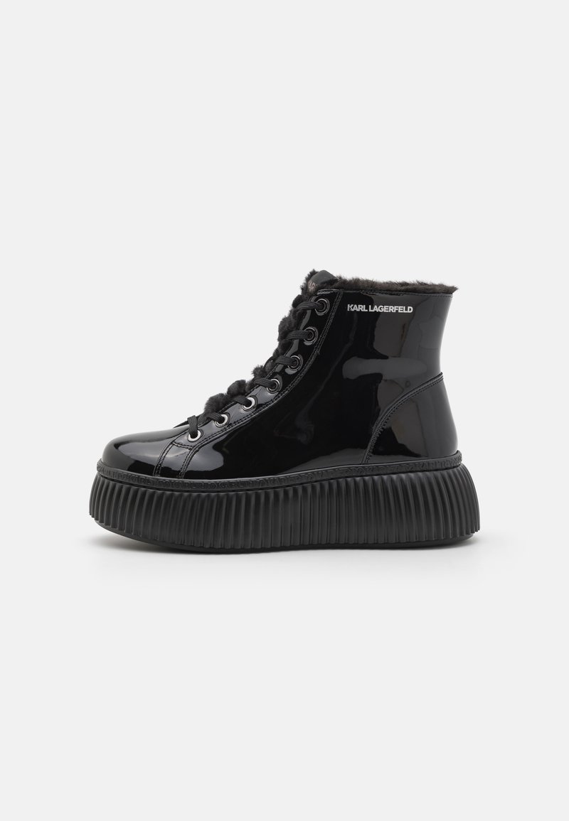 Zwarte gepatineerde leren enkelboots met een textured, gegroefde zool, voorzien van een bontkraag en vetersluiting. Het logo aan de zijkant is zichtbaar.
