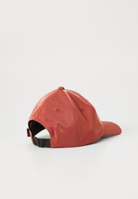 Casquette de baseball rouge avec une finition brillante, vue de côté, dotée d'une sangle noire réglable à l'arrière. Le fond est blanc uni.