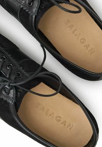 Černé semišové boty s hladkým koženým akcentem, kulatou špičkou, prošitými detaily a šněrováním. Na stélce je vyraženo "BALAGAN".