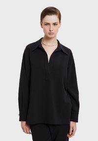 Mustat pitkät hihat -paita, jossa on rento istuvuus, kaulakuvio ja napittomat etuosat. Ominaisuuksiin kuuluu sileä pinta ja hienovaraiset sivuhalkiot.