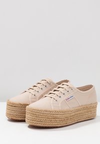 Scarpe platform in tela beige con suola in juta intrecciata, punta rotonda, occhielli in metallo e design con lacci. Presenta un dettaglio del logo sul lato.