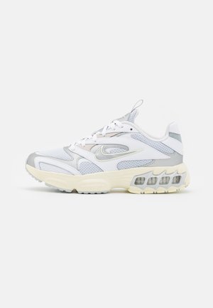 Chaussure de course Nike blanche et grise avec panneaux en maille, semelle amortie avec poches d'air visibles, et fermeture à lacets.