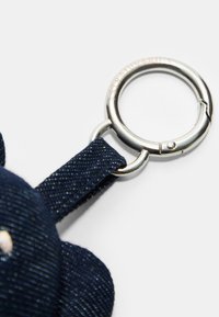 Porte-clés en tissu bleu marine avec un anneau en métal argenté. Le tissu a un tissage texturé, et l'anneau est circulaire avec un fermoir refermable.