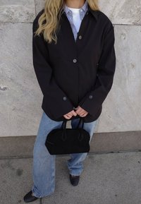 Must have suur suuruse must jope nööpidega, millega on kombineeritud valge ja sinise triibuga särk. Heledast sinisest laia säärega teksad ja väike must seemisnahk käekott.