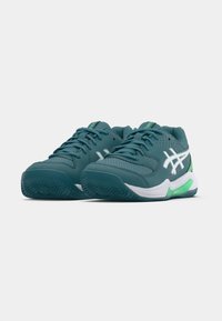 Türkise Sportschuhe mit einem Mesh-Obermaterial, weißen Akzenten und einer grünen Sohle. Sie haben eine abgerundete Spitze und eine profilierte Gummiaußensohle für besseren Halt.