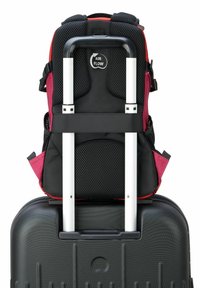 Valise rigide noire avec une surface texturée, surmontée d'un sac à dos noir et bordeaux en mesh et tissu, doté de bretelles réglables et d'une poignée rétractable.