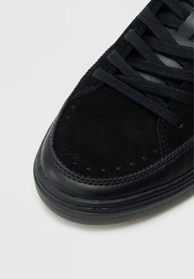 Μαύρο αθλητικό παπούτσι με επάνω μέρος από σουέτ και δερμάτινες λεπτομέρειες, στρογγυλή μύτη, επίπεδα κορδόνι�α, διάτρητα διακοσμητικά στοιχεία και υφασμένο λαστιχένιο πέλμα.