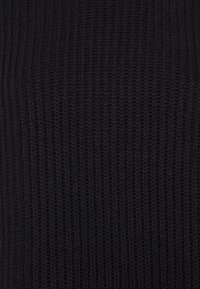 Tissu en tricot noir à côtes verticales. Le matériau semble doux avec une surface texturée, adapté aux vêtements ou aux pièces confortables.