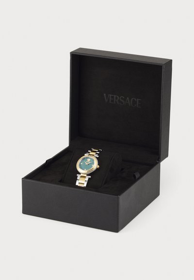 Versace watch in a black box. The watch features a round turquoise dial, gold and silver metal band, and a decorative bezel.