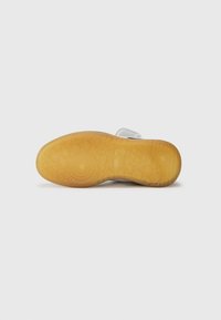 Sneakersåle i klart gummi med et teksturert sirkulært mønster, med en lys grå overdel og semsket aksenter, som gir grep og holdbarhet.