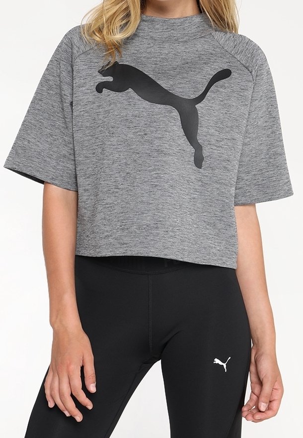 Personne portant un t-shirt court gris Puma et des leggings noirs Puma, tous deux affichant le logo Puma en noir et blanc.