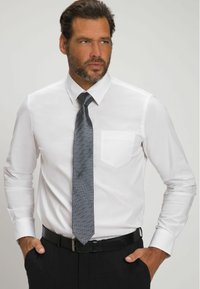 Camisa blanca de vestir con mangas largas y un bolsillo en el pecho izquierdo, acompañada de una corbata gris texturizada y un cinturón negro, combinada con pantalones oscuros.