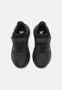 Chaussures de sport noires avec une tige en mesh et synthétique. Comprend un système de fermeture à lacets et une sangle Velcro, un col rembourré et une semelle texturée.