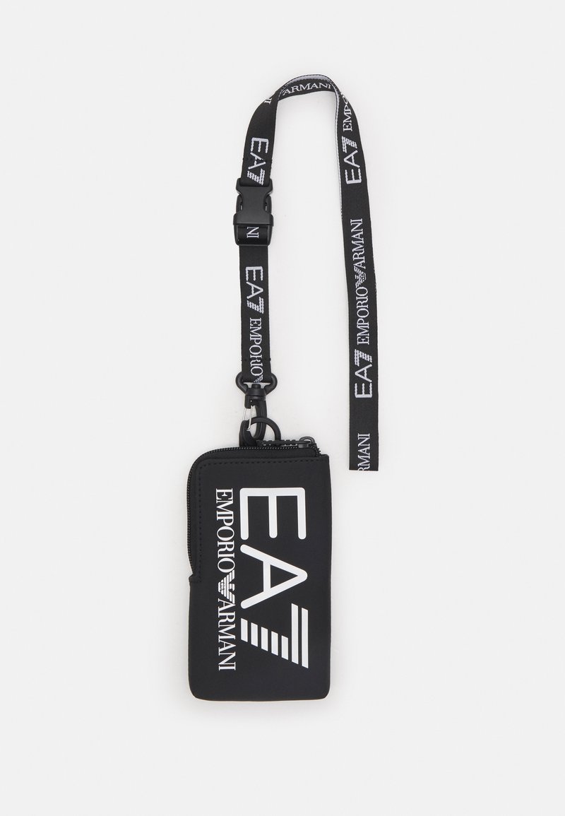 Musta tõmblukuga kotike, mis on valmistatud pehmest materjalist, sellel on silmatorkav valge Emporio Armani logo ja eemaldatav kaelarihm logo mustriga.
