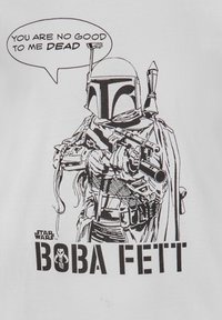 T-shirt graphique noir et blanc présentant une illustration détaillée d'une figure casquée tenant des armes, avec une bulle de texte disant : "TU NE ME SERS À RIEN MORT."