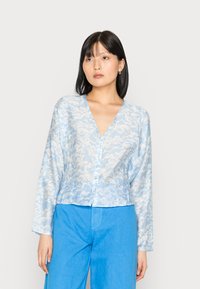 Blusa botão azul claro com um padrão de ondas, feita de um tecido transparente, apresentando um decote em V profundo e mangas longas.