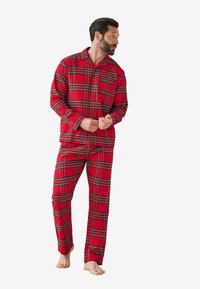Røde ternede pyjamaser med en knap-op skjorte med krave og lange ærmer, sammen med matchende bukser. Materialet ser blødt og hyggeligt ud.