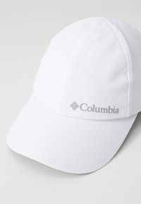 Cappello bianco in tessuto liscio, con visiera curva e logo grigio Columbia sul frontale. Include fori di ventilazione sui lati.