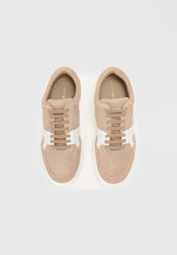 Beežid suedsneakerid valgete detailidega, ümmargune ninaosa, kuus silmaauku ja lace-up esiosa, tekstuuriga ülemine osa ning lame valge kummist tall. 