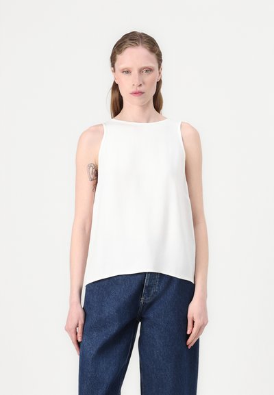 Top sans manches blanc avec un décolleté droit, fabriqué en tissu lisse, présentant une coupe décontractée et un ourlet légèrement plus long à l'arrière.