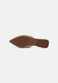 Semelle d'une chaussure à bout pointu avec semelle extérieure en caoutchouc marron texturé et talon bloc bas sur fond blanc.