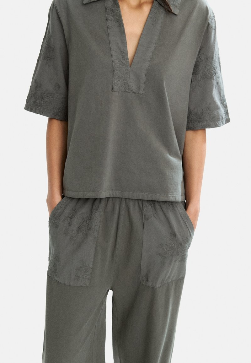 Top de algodón gris con escote en V y mangas cortas, con bordados florales. Combinado con pantalones holgados a juego con bolsillos y acentos bordados.
