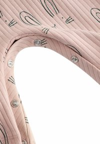 Randig rosa tyg med gröna kaninmönster, med metallknäppningar längs halsringningen för enkel påklädning. Mjuk textur.
