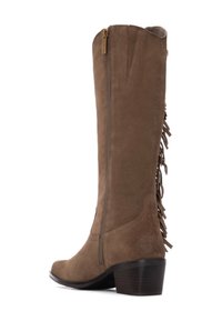 Botín de ante marrón hasta la rodilla con un tacón apilado, cremallera lateral y detalle de flecos en la parte trasera. Textura suave con costuras definidas.