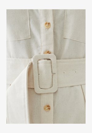 Helebeige linane kleit nupuga sulgemisega, suurte rinnataskutega ja laia vööga, millel on ristküliku kujuline metsik ja mitu auku.