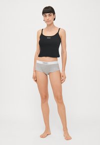 Fekete, cropped tank top vékony pántokkal és fehér logóval, szürke pamut boxer alsóneművel, fehér derékkal és logó részlettel párosítva.