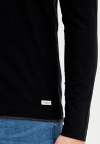 Schwarzes Langarmshirt aus einem weichen Baumwoll-Mix, mit einem kleinen weißen Etikett "BLEND DENIM" am Saum. Slim Fit mit glatter Textur.