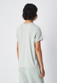 T-shirt vert clair à manches courtes, encolure ronde, en coton doux, coupe décontractée, avec des détails de couture subtils le long des bords.