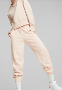 Felpa rosa chiaro con design corto e pantaloni jogger abbinati. Tessuto morbido, vita elasticizzata e polsini a coste. Stile minimalista.