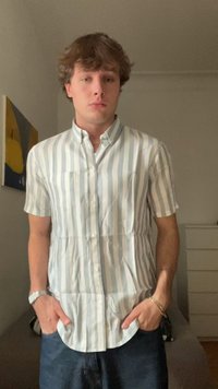 Short-sleeve button-up shirt with light blue and white vertical stripes, featuring two front pockets and a pointed collar. Smooth fabric texture.