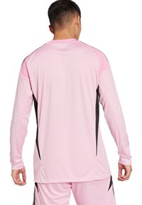 Maglietta atletica rosa a maniche lunghe con dettagli neri ai lati e colletto a girocollo, realizzata in un tessuto liscio, leggero e elasticizzato. Vista posteriore mostrata.
