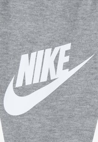 Grauer Stoff mit einem auffälligen weißen Nike-Logo und Swoosh, mit einer weichen Textur und einfachem Design.