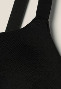 Black padded bralette with textured black fabric, featuring adjustable straps and a rounded neckline. Minimalist design, smooth surface.